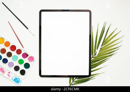 Draufsicht auf das Tablet mit leerem Bildschirm und Eingabestift Auf Tisch mit Skizzenbuch und bunten Filzstiften Stockfoto