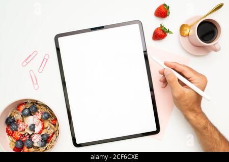 Draufsicht auf den Mann, der am Tisch mit Frühstück sitzt Schüssel und Tasse Espresso während der Erstellung digitaler Skizze Stockfoto