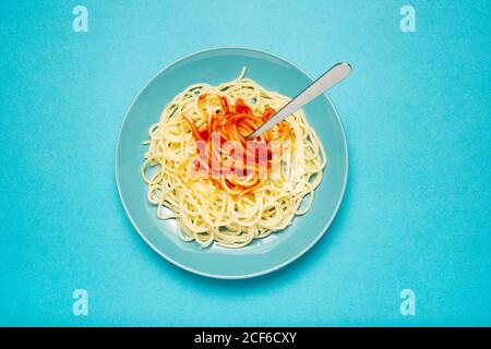 Draufsicht auf blaue Keramikplatte mit Pasta und Tomate Sauce auf hellblauem Hintergrund Stockfoto