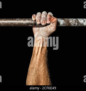 Unerkennbarer Sportler greift Bar mit Hand mit Kreide bedeckt Schwarzer Hintergrund beim Training im Fitnessstudio Stockfoto