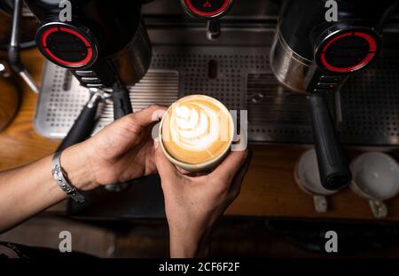 Von oben Ernte Hände von professionellen Mitarbeiter, die Cappuccino mit Muster oben im Coffee Shop Stockfoto
