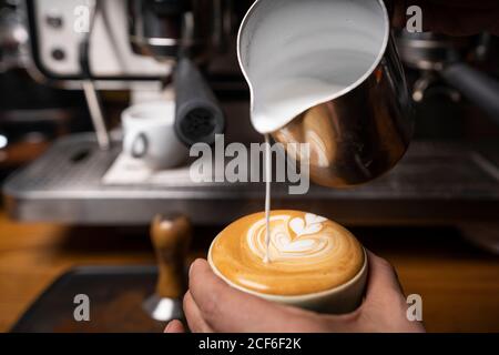 Von oben Ernte Hände von professionellen Mitarbeiter, die Cappuccino mit Muster oben im Coffee Shop Stockfoto