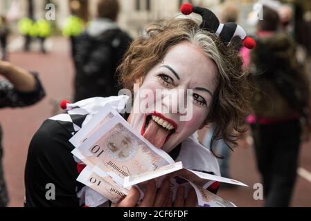 London, Großbritannien. September 2020. Ein Clown hält Banknoten zusammen mit anderen Klimaaktivisten von Extinction Rebellion, die an einem ‘Karneval der Korruption’ Protest gegen die Unterstützung und Finanzierung der fossilen Energiewirtschaft durch die Regierung teilnehmen. Extinction Rebellion-Aktivisten nehmen an einer Reihe von Rebellion-Protesten im September in Großbritannien Teil, um Politiker aufzufordern, das Klima- und ökologische Notstandsgesetz (CEE Bill) zu befürworten, das unter anderem Maßnahmen wie Ein ernsthafter Plan, um den Anteil Großbritanniens an den Emissionen zu bewältigen und den kritischen Anstieg der globalen Temperaturen zu stoppen und für die einfachen Menschen zu mir zu werden Stockfoto