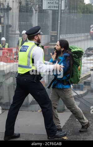 London, Großbritannien. September 2020. Ein Polizeibeamter verhindert das Aussterben eines Klimaaktivisten Rebellion kann sich anderen Aktivisten anschließen, die sich vor dem Parlament auf den Bürgersteig geklebt hatten. Extinction Rebellion-Aktivisten nehmen an einer Reihe von Rebellion-Protesten im September in Großbritannien Teil, um Politiker aufzufordern, das Klima- und ökologische Notstandsgesetz (CEE Bill) zu befürworten, das unter anderem Maßnahmen wie Ein ernsthafter Plan, um mit dem Anteil Großbritanniens an den Emissionen umzugehen und kritische Temperaturanstiege zu stoppen und damit die einfachen Menschen in zukünftige Umweltbelange einbezogen werden Stockfoto