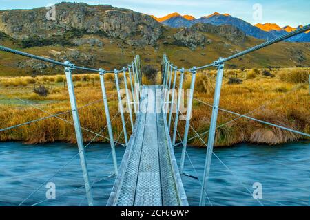 Hängebrücke über einen alpinen Fluss mit Aussicht. Dies war einer der Orte für Herr der Ringe Filme. Edoras, die Hauptstadt von Rohan sonst wissen Stockfoto