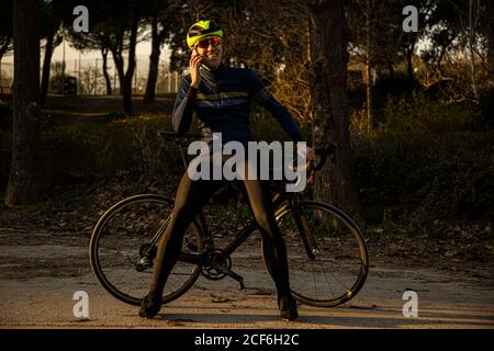 Mann, der sich in einem Park auf der Fahrradspur mit dem Mobiltelefon ausruhte Stockfoto