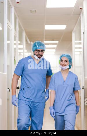 Chirurgen-Mitchirurgen, Mann und Frau unterhalten sich, während sie zum Operationssaal gehen Stockfoto