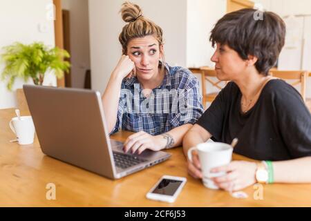 Zwei schöne und junge Frauen beim Frühstück zu Hause und Mit dem Laptop Stockfoto