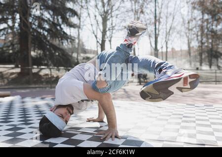 Junge bärtige Kerl in Freizeitkleidung tun Kopfstand im Park Bei sonnigem Wetter Stockfoto