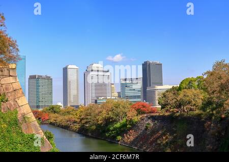 Wunderschöne Stadtlandschaft mit bunten Wäldern und Fluss im Vordergrund, Blick vom Osaka Castle Park im Herbst, Osaka, Japan
