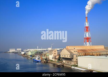 Laderaum Japan Coastal Ship ist am Industriehafen von Fabrikgebäuden an der Osaka Bay, Japan, vertäut. Stockfoto