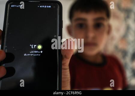 Idlib, Syrien. September 2020. Ein syrischer Junge zeigt Wetter-App in seinem Handy an einem heißen Sommertag, als starke Hitzewelle die Stadt Idlib trifft, 03. September 2020. (Foto von Azalden Idlib/INA Photo Agency) Quelle: SIPA USA/Alamy Live News Stockfoto