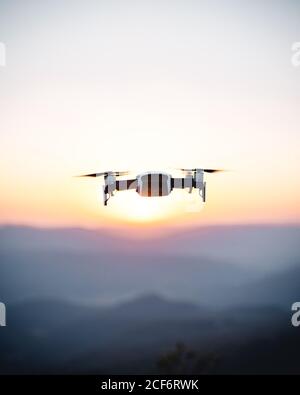 Schwarz-weiß fliegende Drohne hoch in Sonnenuntergang Himmel Stockfoto