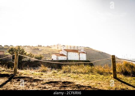 Malerischer Blick auf kleine weiße Steinkirche mit rotem Dach Auf sonniger Klippe in einem kleinen Dorf in der Landschaft von Spanien Stockfoto