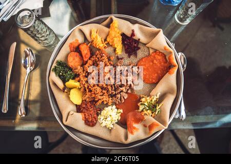 Traditionelles äthiopisches Gericht von Injera mit Fladenbrot und verschiedenen Gemüsesorten Serviert auf dem Tisch Stockfoto