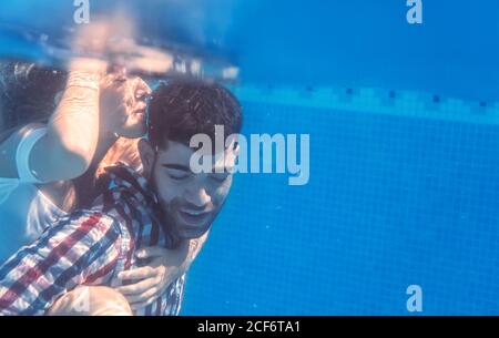 Frau Mann in Kleidung unter Wasser und lächelnd umarmen. Stockfoto