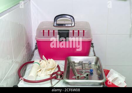 Pinke Kunststoffbox zum Tragen von Katzen und medizinischen Werkzeugen Chirurgische Tablett von gefliesten Wand in der Tierklinik Stockfoto