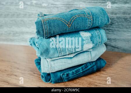 Jeans-Hosen im Regal im Bekleidungsgeschäft - Viele blaue Schattierungen von Denim Haufen von Kleidung auf Holz Regale Stockfoto