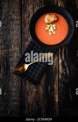 Hausgemachte typisch spanische Gazpacho von oben. Salmorejo. Tomatensuppe mit Gurke; grüner Pfeffer, Brot und Olivenöl auf dunklem Holzhintergrund. Spanisches Essen. Flach liegend. Stockfoto