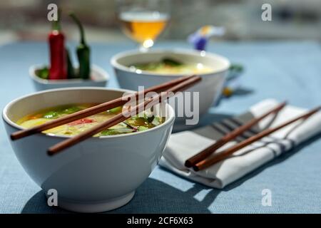 Von oben orientalischer Ramen gesunde Nudelsuppe mit Shiitake, Spinat, Karotten, Eiern und Chilis auf dem Restauranttisch Stockfoto