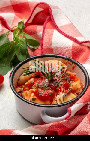 Gekochte Ravioli mit Tomatensauce und Kräutern auf Sauce Pfanne Kasserolle neben Tomaten auf Tuch in einem Tisch Stockfoto