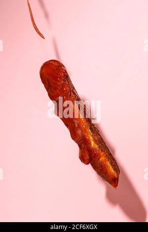 Köstliche gegrillte Wurst voller Ketchup in einem rosa Hintergrund Stockfoto