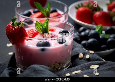 Hausgemachter Joghurt mit Erdbeeren, Heidelbeeren und Getreide mit dunklem Hintergrund und Sonnenlicht.gesundes Lebensmittelkonzept.Veganes Essen Stockfoto