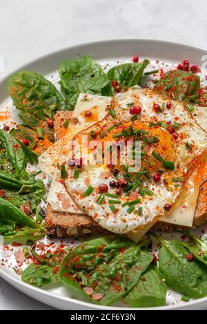 Hausgemachtes geröstetes Brot mit Spiegelei, Spinat und aromatischen Kräutern auf weißem Hintergrund.Vegetarisches Essen.gesundes Lebensmittelkonzept. Stockfoto