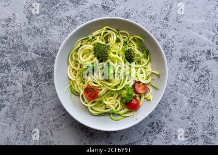 Hausgemachte Zucchini-Spaghetti mit Pesto-Sauce, Brokkoli und Kirschtomaten von oben. Veganes Lebensmittelkonzept.Flat Lay.Draufsicht Stockfoto