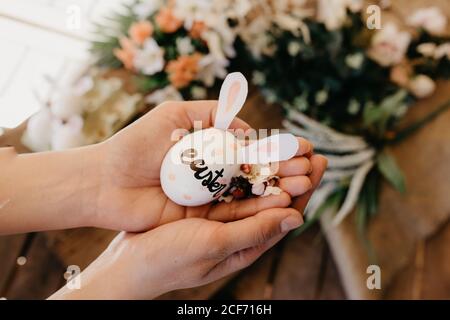 Junge Frau hält ein osterei mit Hasenohren, die von Kindern mit Blumen gemalt wurden Stockfoto