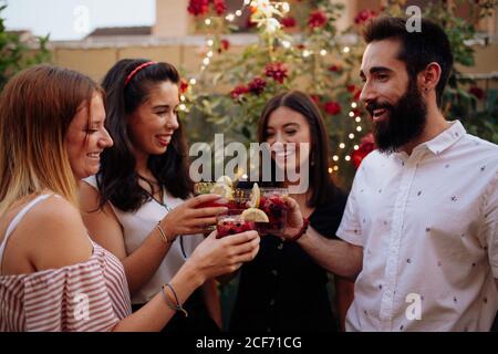 Gruppe von lächelnden Hipster junge Freunde klirren Gläser mit bunten beerengetränke bei der Sommerhofparty Stockfoto