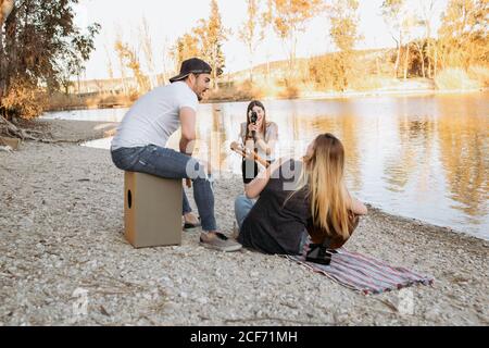 Junge Frau, die auf eine Freundin schießt, die Gitarre spielt Stockfoto