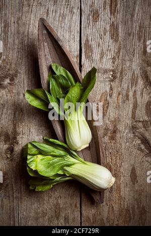 Draufsicht auf reifen Bok Choy in der Nähe von Holzplatte platziert Auf einem schäbigen Holztisch in der Küche Stockfoto