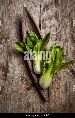 Draufsicht auf reifen Bok Choy in der Nähe von Holzplatte platziert Auf einem schäbigen Holztisch in der Küche Stockfoto