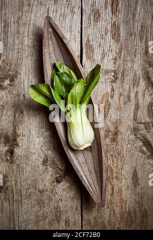 Draufsicht auf reifen Bok Choy in der Nähe von Holzplatte platziert Auf einem schäbigen Holztisch in der Küche Stockfoto