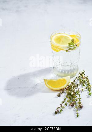 Gläser mit erfrischendem kaltem Thymian und Ingwerlimonade mit Scheiben Von Zitronen- und Minzblättern serviert auf dem Tisch in Licht Zimmer Stockfoto