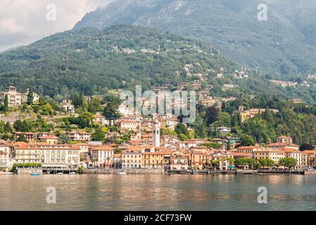 Panorama von Menaggio Stadt am Comer See in Italien. Helle Architektur mit bunten Gebäuden. Stadtufer mit Touristen. Blick vom Wasser. Stockfoto