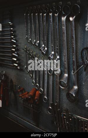 Set von verschiedenen Reparaturwerkzeugen an der grungy Metallwand befestigt In der professionellen Werkstatt Stockfoto