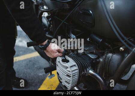 Anonymer männlicher Befestigungsmotor des Motorrads auf Parkplatz auf City Street Stockfoto