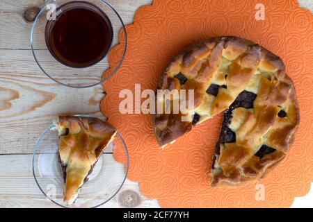 Hausmannskost, eine Torte, ein Stück Apfelkuchen gefüllt mit Kirschen und Walnüssen und eine Tasse Tee sind auf dem Tisch Draufsicht Stockfoto