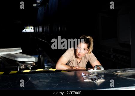 Attraktive Soldatinnen, die in der Dunkelheit sitzen und die Kamera betrachten hangar Stockfoto