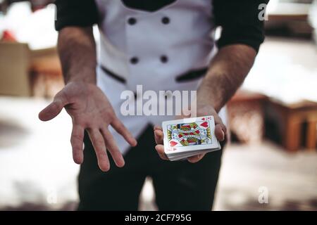 Crop unkenntlich männlich zeigt Stapel von Spielkarten mit Rot König der Herzen Karte auf der Oberseite, während sich gegen verschwommen Hintergrund Stockfoto