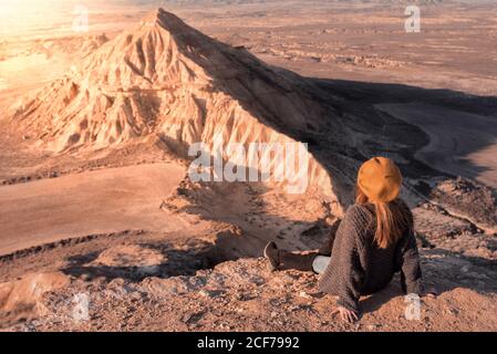 Stilvolle Frau, die auf einer Klippe in Badlands sitzt Stockfoto