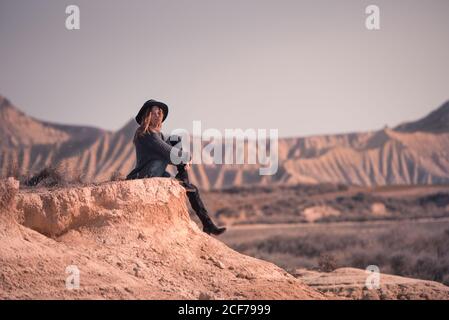 Stilvolle Frau, die auf einer Klippe in Badlands sitzt Stockfoto