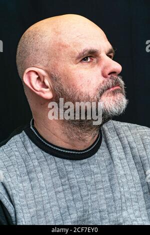 Porträt eines kahlen Bartmenschen mittleren Alters im Profil auf schwarzem Hintergrund Stockfoto