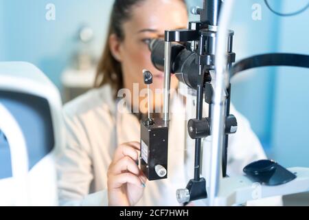 Junge medizinische Arbeiter suchen und mit Mikroskop am Arbeitsplatz auf Unscharfer Hintergrund Stockfoto