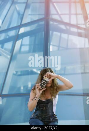 Junge Frau, die in der Stadt mit der Kamera fotografiert Stockfoto