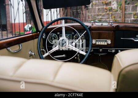 Ansicht des schwarzen Metalllenkrads und des Armaturenbretts mit Front Beigefarbene Sitze im klassischen Auto Stockfoto
