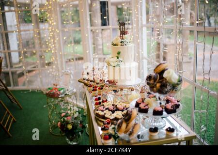 Festlich dekorierte süße Kuchen Muffins und weiß geblümten Kuchen auf Stehen Sie im Restaurant Stockfoto