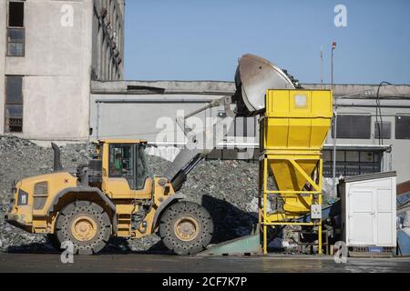 Bukarest, Rumänien - 1. September 2020: Erdbeweger-Betreiber, der einen Stapel leerer Flaschen in einer Glasrecyclinganlage arrangiert. Stockfoto